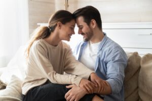 Husband and wife having an open, vulnerable conversation at home, one spouse sharing while the other listens with presence, showing how to communicate authentically with your spouse.